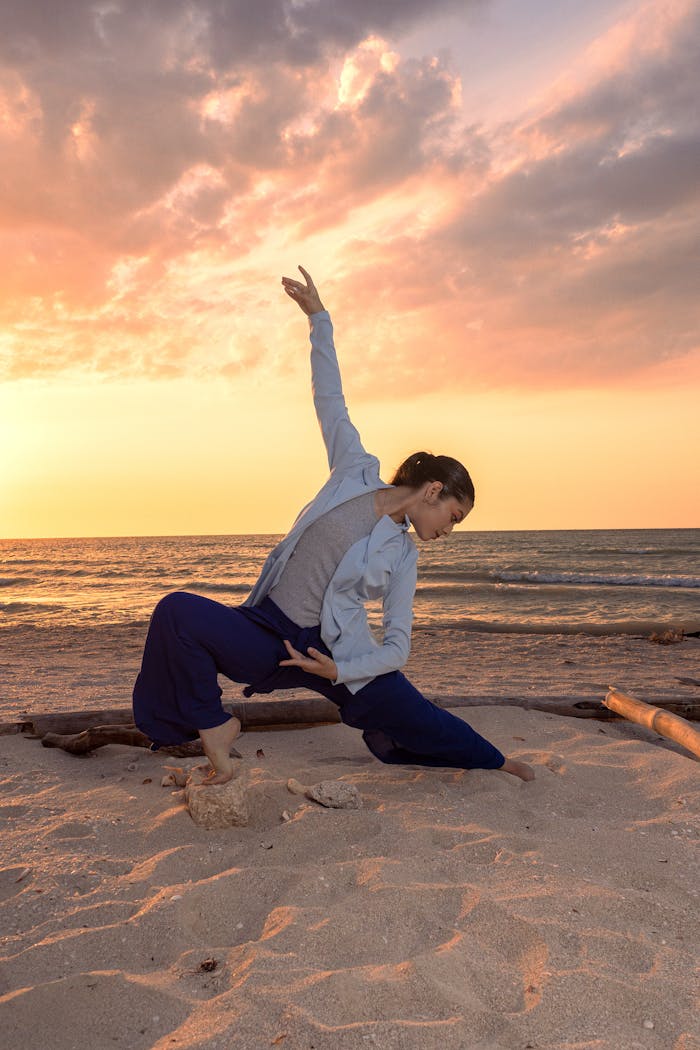 A woman gracefully poses on Sisal Beach, México at sunset, showcasing yoga and serene landscapes.