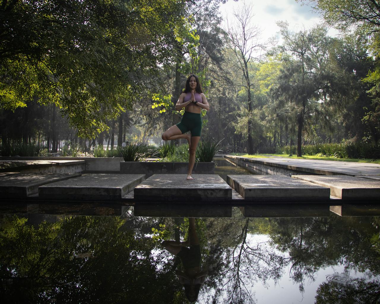 services-01 Woman practicing yoga by a reflective pond in a Mexico City park, showcasing tranquility and natural beauty.