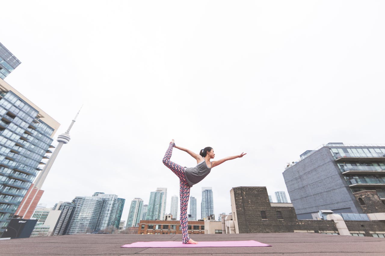 services-02 A woman performs yoga on a rooftop overlooking a modern city skyline, embodying balance and urban tranquility.