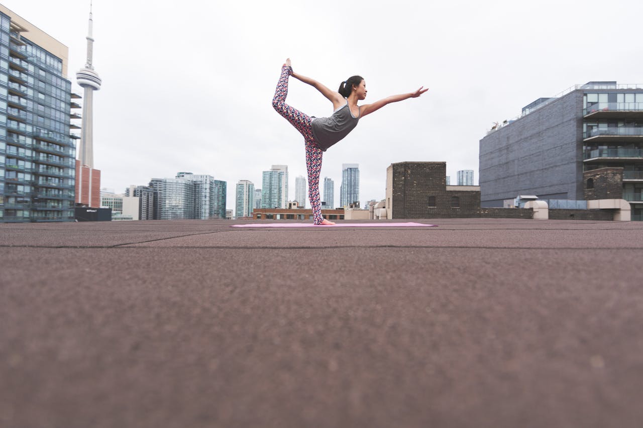 Woman practicing yoga on a rooftop with Toronto skyline in the background.